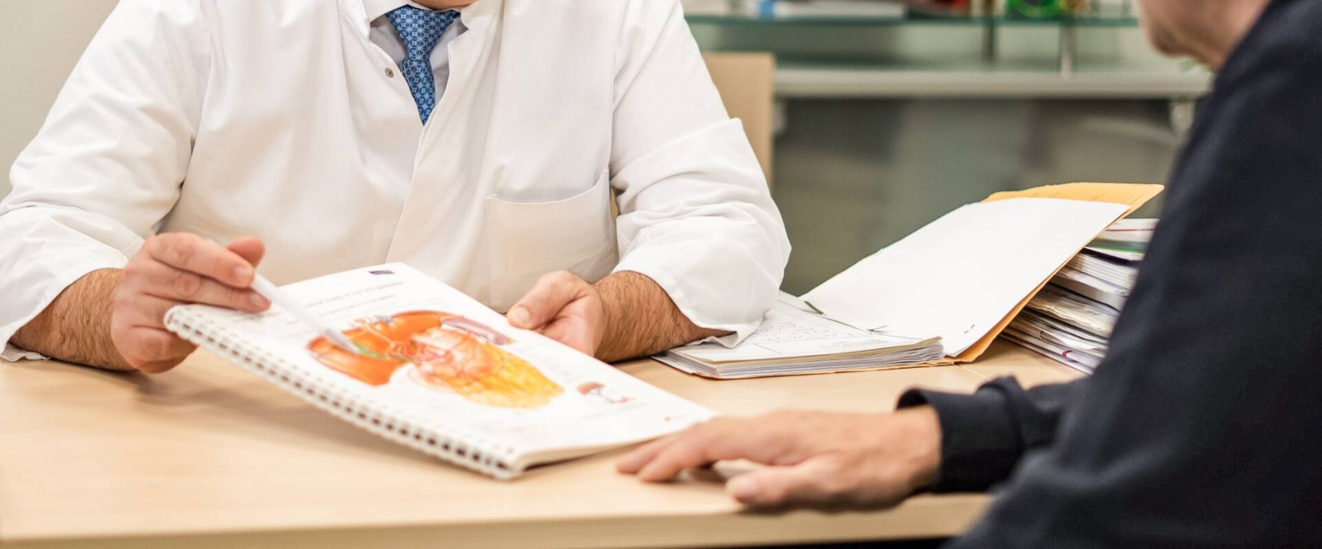 Schreibtisch von Arzt, der Patienten anhand einer Grafik etwas erklärt