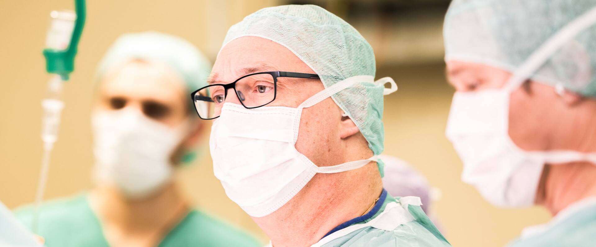 Drei Ärzte in OP in Nahaufnahme in OP-Montur während einer Operation