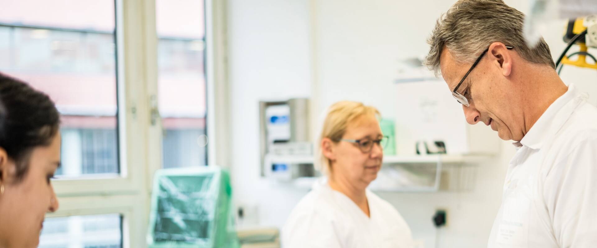 Behandlungsraum mit Pflegerinnen und einem Arzt, die Untersuchung vorbereiten